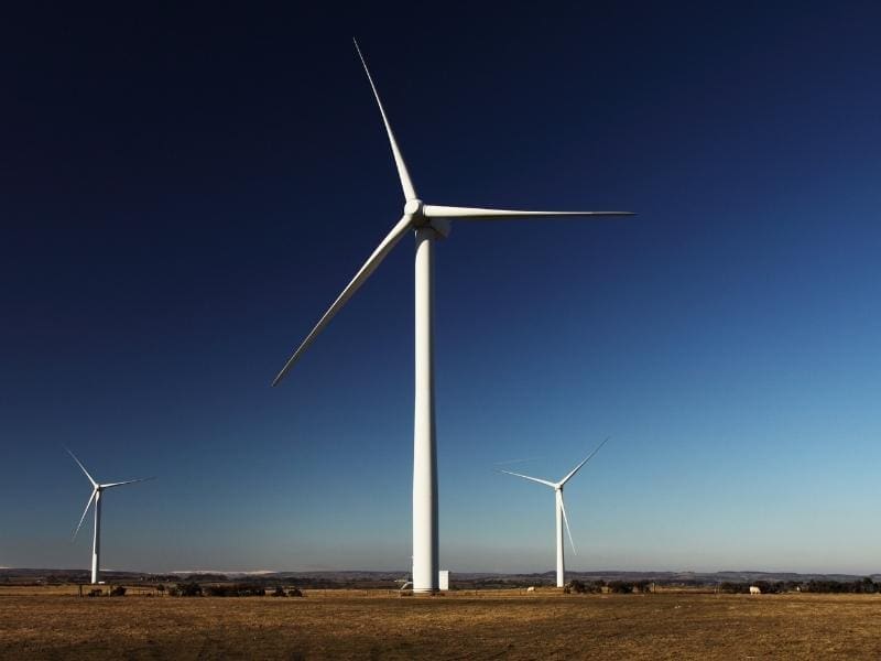 Three large wind turbines in a sunset